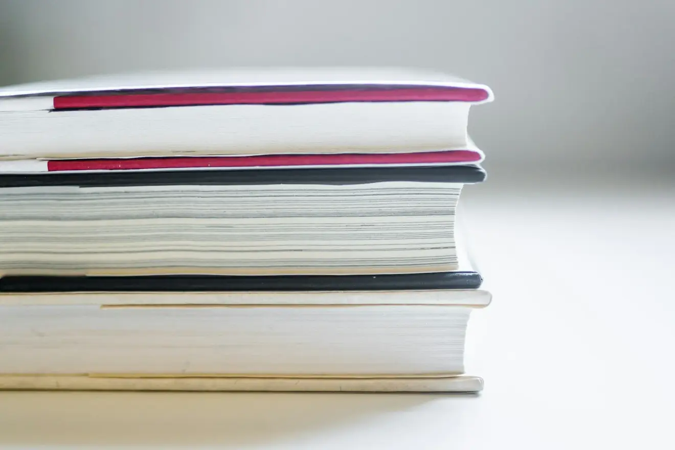 A horizontal stack of books with red, black and cream covers