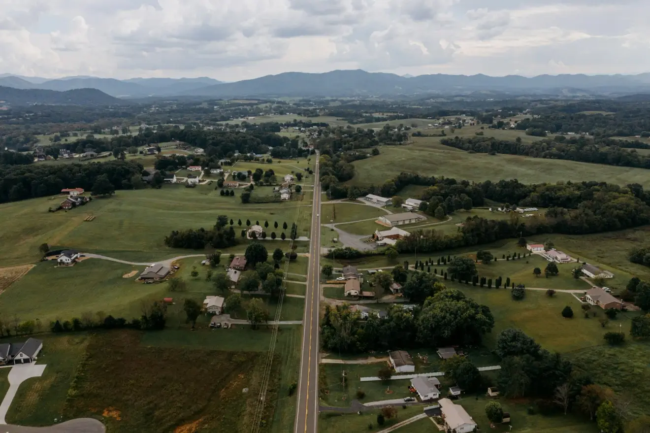 Rural homes, fields and a road beneath distant mountains near Greeneville, Tennessee