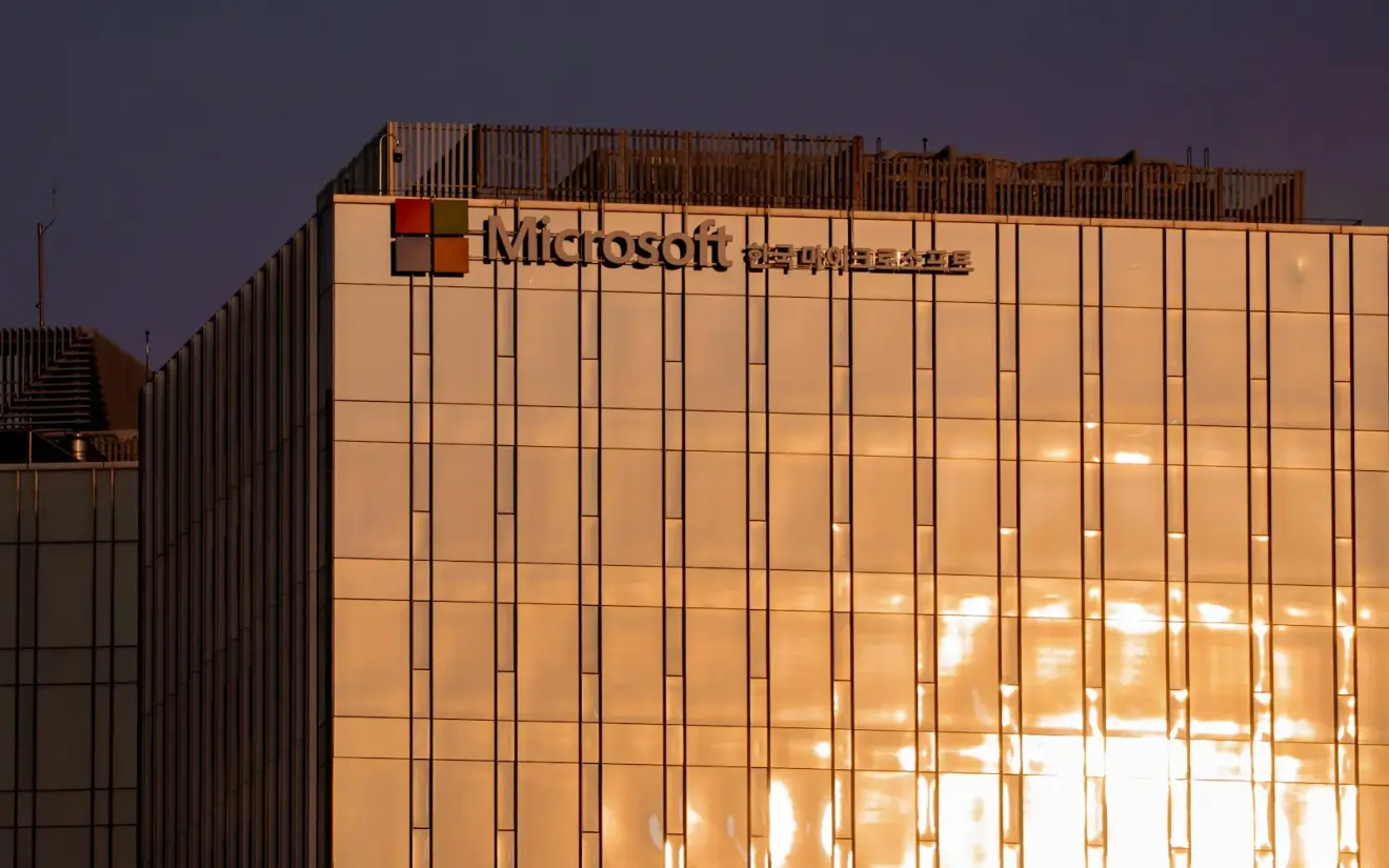 Microsoft signage on a glass office building reflecting golden evening light