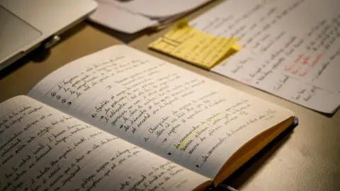 Open notebook with handwritten study notes beside a laptop