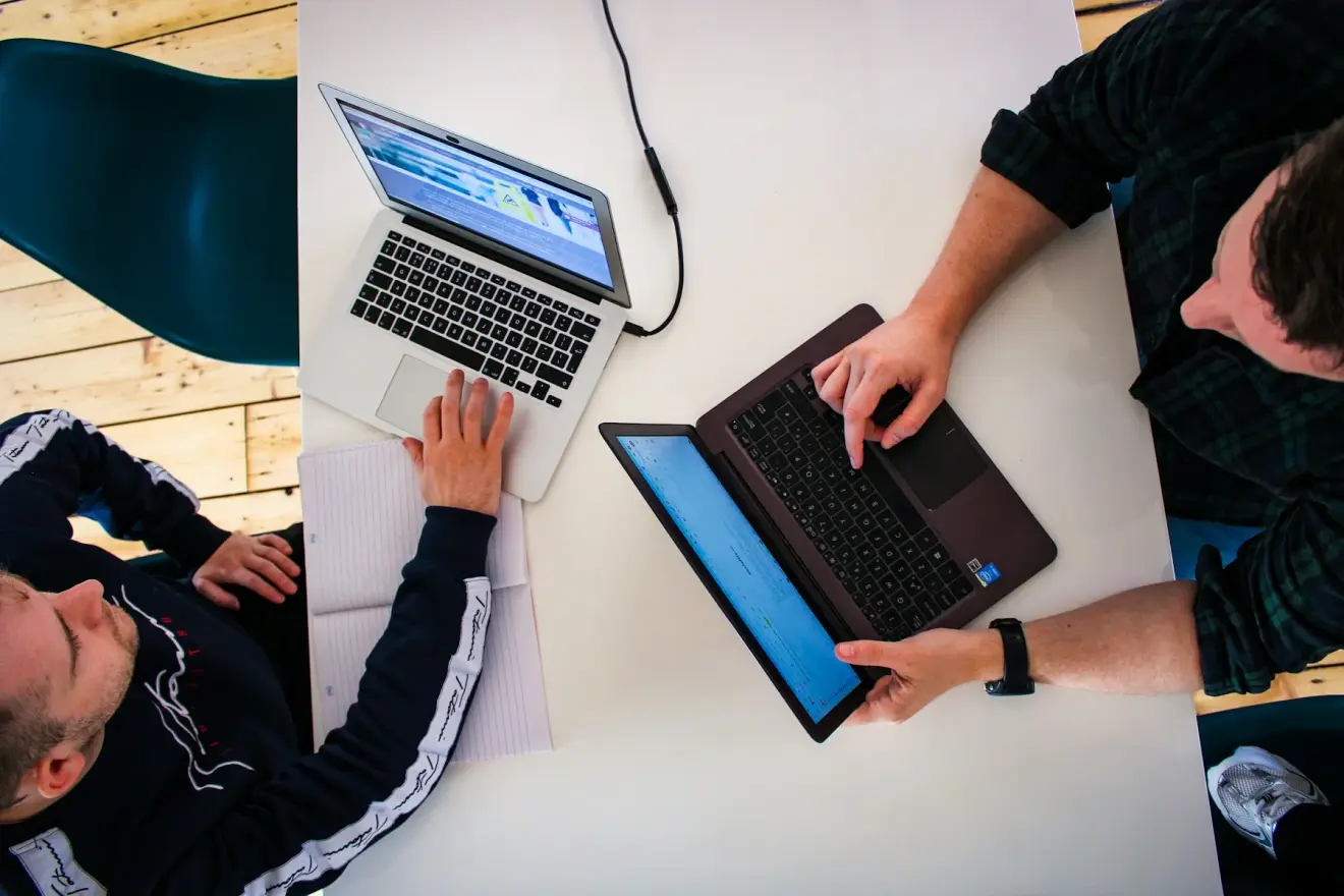 Overhead view of two colleagues working on laptops at a shared table