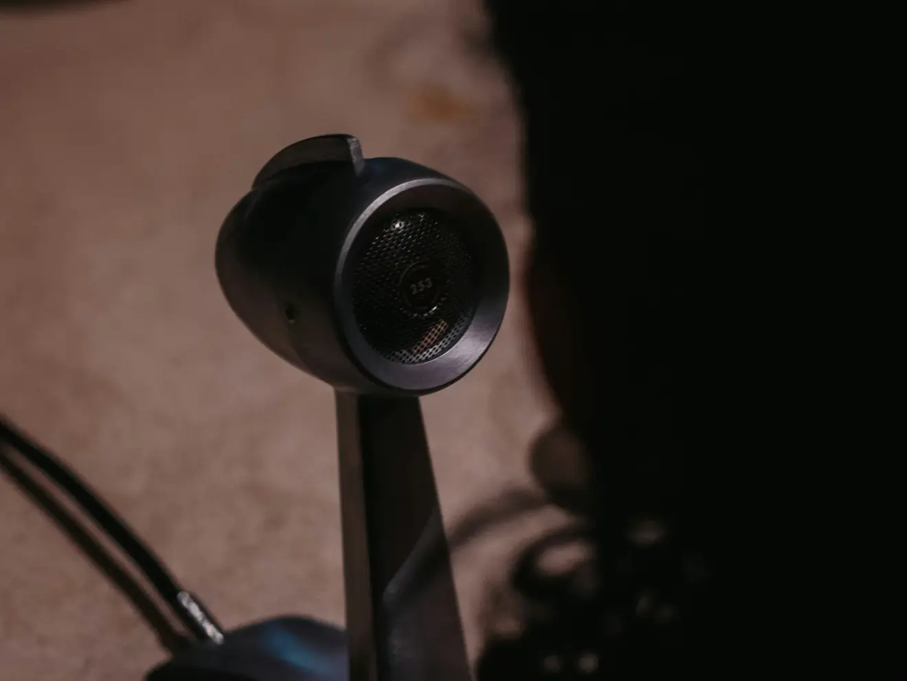A vintage round microphone on a stand in a dim recording space.